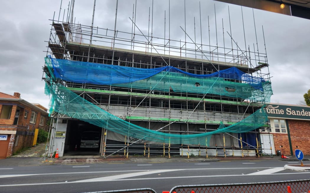 The front view of the unfinished Epsom apartments, covered in netting and scaffolding.