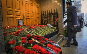 A man lays flowers to Azerbaijan's Embassy in Moscow on December 26, 2024 paying tribute to the victims of Azerbaijan Airlines' plane crash. - The Kremlin on December 26, 2024 cautioned against "hypotheses" over the crash of an Azerbaijani plane which had been due to land in Russia as experts pointed to possible evidence of a missile explosion. The Azerbaijan Airlines jet crashed near the Kazakh city of Aktau, an oil and gas hub, on December 25, 2024. Thirty-eight of the 67 people on board died. (Photo by Alexander NEMENOV / AFP)