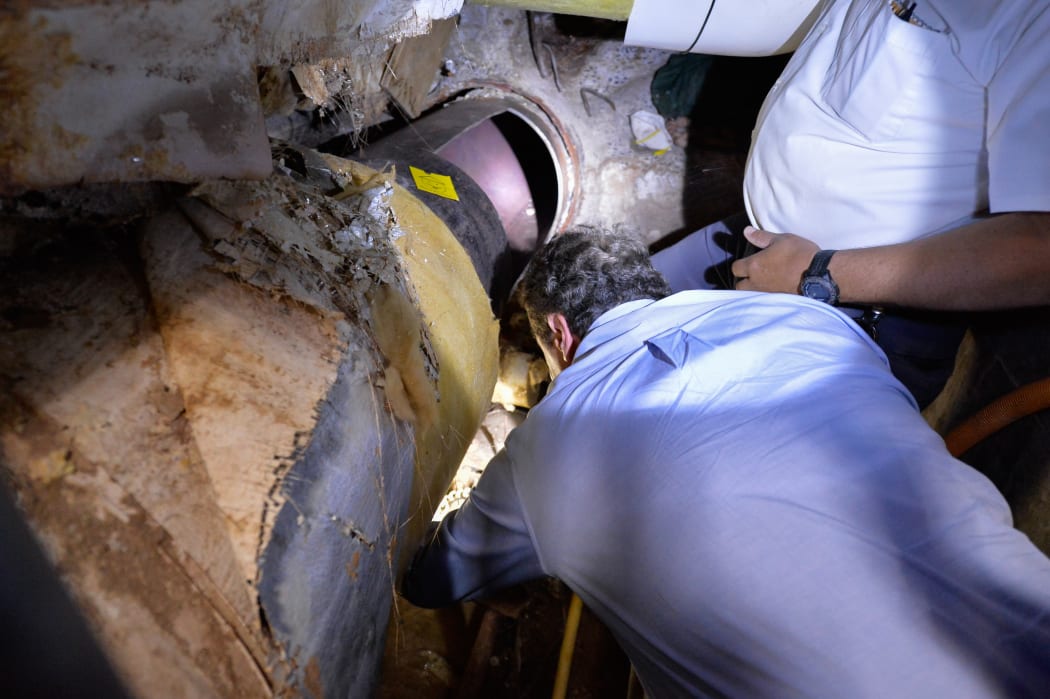New York Governor Andrew Cuomo inspects a pipe cut open in the escape - a note on yellow paper left by the fugitives can also be seen.