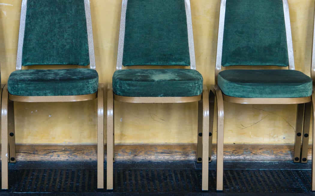 Green chairs lined up against a yellow wall in a waiting area