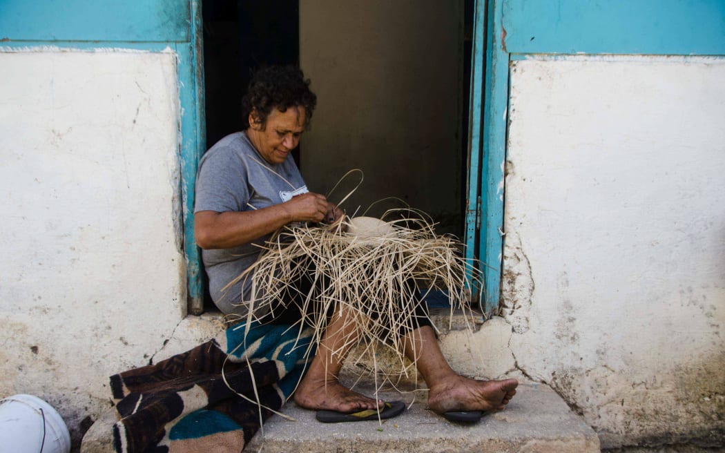 Teremoana, a resident of Mangaia, Cook Islands, weaving a pandanus hat