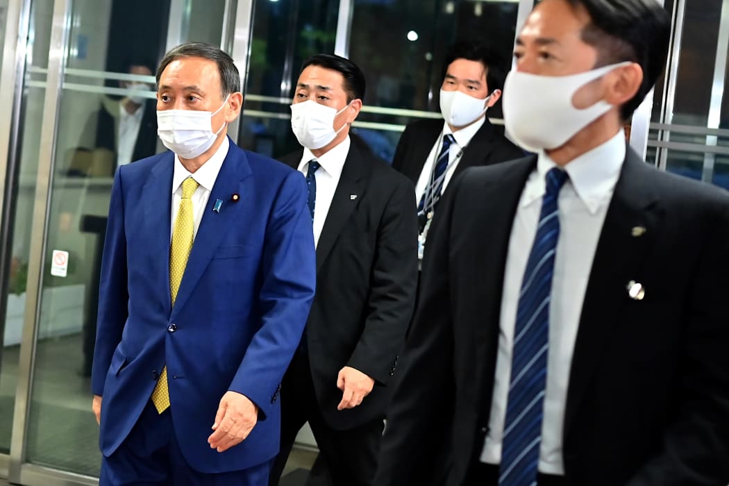 Newly elected leader of Japan's Liberal Democratic Party Yoshihide Suga (L) arrives at the party's headquarters to attend a press conference in Tokyo