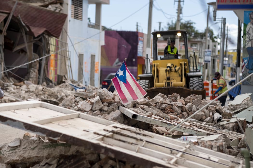 A Puerto Rican flag waves on top of a pile of rubble as debris is removed from a main road in Guanica, Puerto Rico on January 8, 2020, one day after the earthquake.
