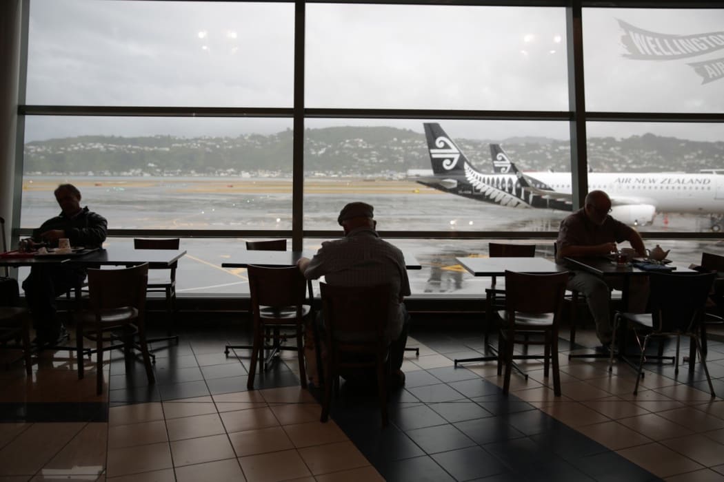 People wait at Wellington airport after foul weather forced the cancellation and delay of dozens of flights.