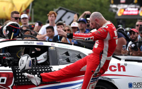 Shane van Gisbergen kicks a rugby ball as part of his celebration for winning the Chicago street race, the Nascar Cup Series Grant Park 165 on July 06, 2025. (Photo by James Gilbert / GETTY IMAGES NORTH AMERICA / Getty Images via AFP)