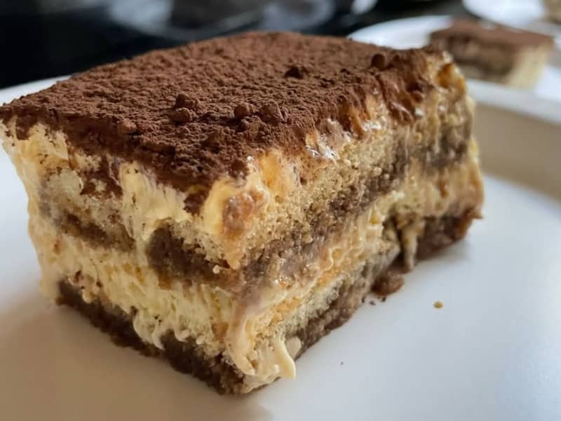 A slice of tiramisu on a white plate.