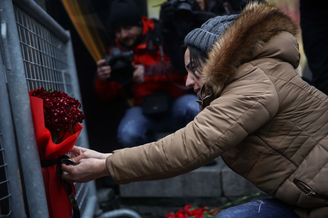 A woman leaves a bouquet of carnation at site to pay tribute to victims of Istanbul night club terror attack in Istanbul, Turkey on January 01, 2017.