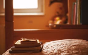 Some books on the bed in the calm ambiance of teenager's room.