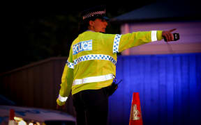 A police officer directing traffic at an alcohol check point.