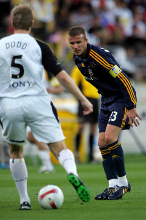 New Guam football coach Karl Dodd passes the ball as David Beckham watches on during a match between Wellington Phoenix and LA Galaxy in 2007.