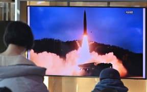 People watch a television screen showing a news broadcast with file footage of a North Korean missile test, at a railway station in Seoul on January 30, 2022, after North Korea fired a "suspected ballistic missile' in the country's seventh weapons test this month according to the South's military.