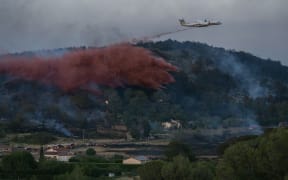 A DASH firefighting aircaft drops fire retardant during a wildfire near Bizanet, southwest France, on June 29, 2025. (Photo by IDRISS BIGOU-GILLES / AFP)