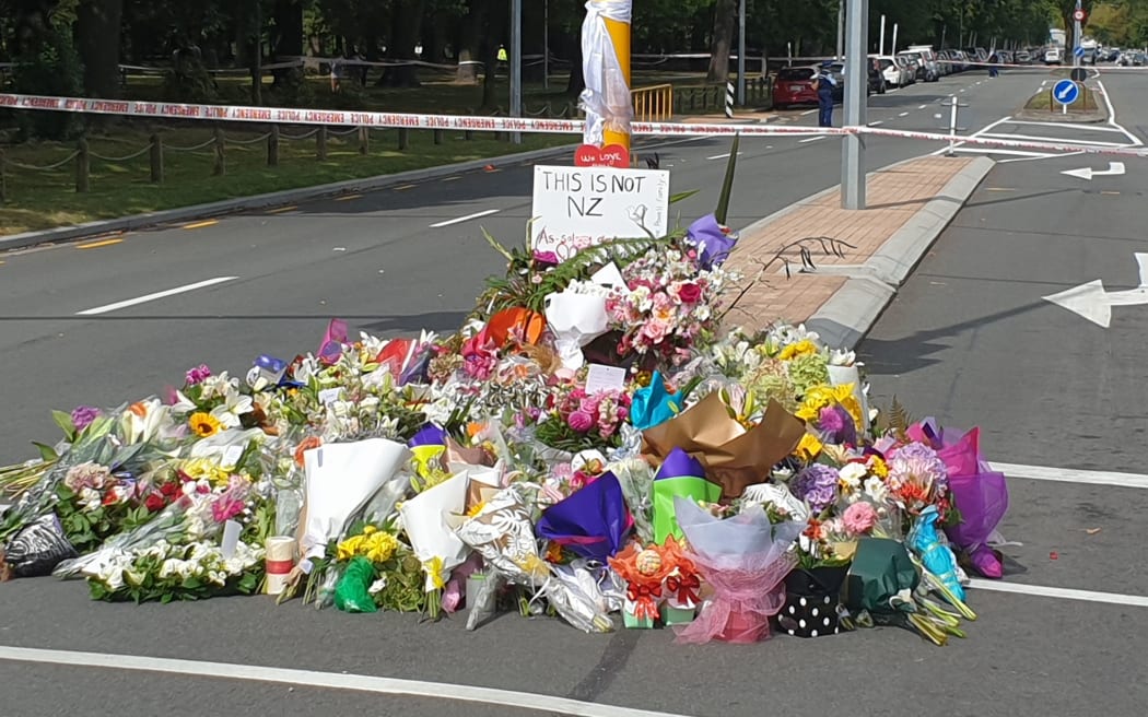 People gather near scene of first shooting to lay flowers
