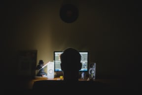 Male in front of a computer screen in the dark.