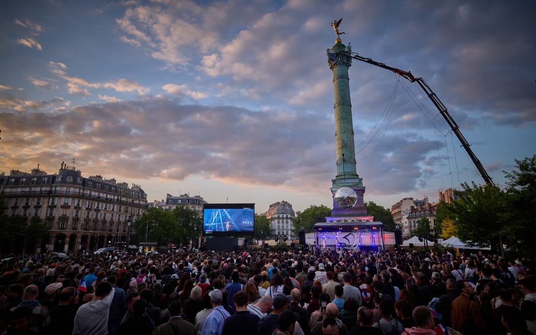 People gather at a fan zone on Place de la Bastille to watch a broadcast of the grand final of the Eurovision Song Contest 2025, which takes place in Basel, Switzerland, in Paris on May 17, 2025.