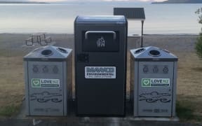 A Bigbelly bin, flanked by two recycling bins