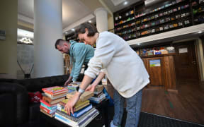 This photograph taken on September 18, 2022, shows Julia Sydorenko and her husband using string to tie up stacks of Russian language books which they brought to the Siayvo bookstore, where they are being collected and prepared for recycling, in Kyiv. - Recycling second-hand Russian-language books to raise funds for the Ukrainian army is a novel sign of the mood for 'de-Russification' since Russia invaded Ukraine in February. The idea to recycle Russian-language books to help the army was inspired by customers at Siayvo who wanted to dispose of the unwanted sections of their home libraries. (Photo by Sergei SUPINSKY / AFP)