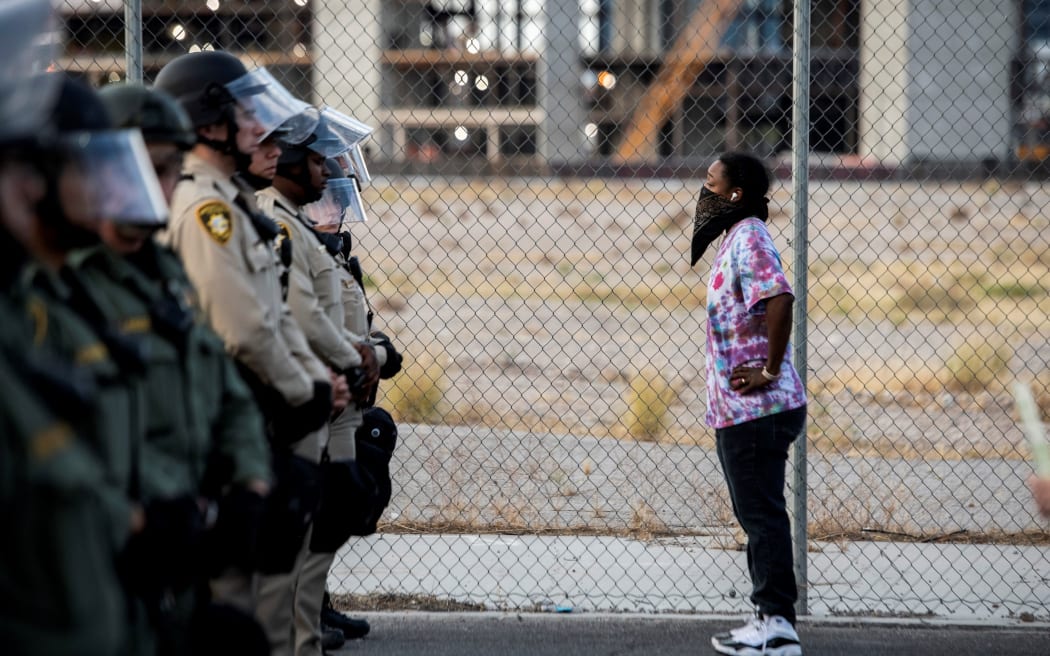 A woman stands in front of police officers, on 1 June  2020, in downtown Las Vegas, in a Black Lives Matter rally.