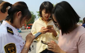 Passengers use smartphones in Qingdao city, east China's Shandong province, 18 June 2019.
