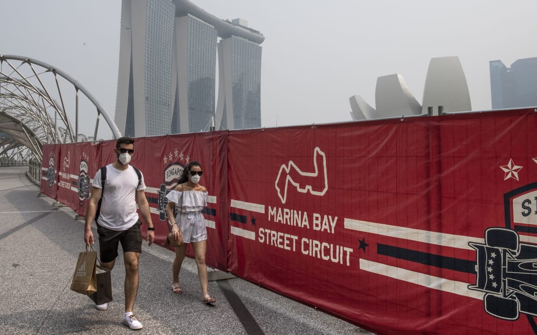 Tourists wear protective masks as they walk near the Formula One Singapore Grand Prix night race track while haze blankets Singapore on September 18, 2019.