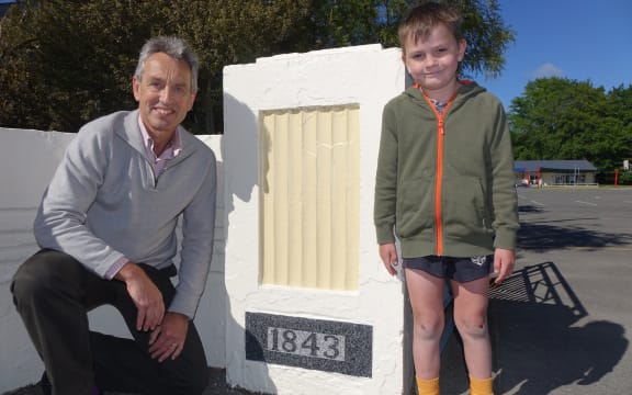 Principal Peter Verstappen with Kyro David Peter Baigent stand beside the sign which marks the opening year of Wakefield School.