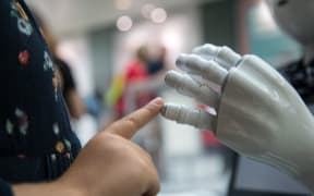 Child's finger touches the hand of a robot