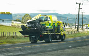 A ambulance on the the back of a truck after a crash.