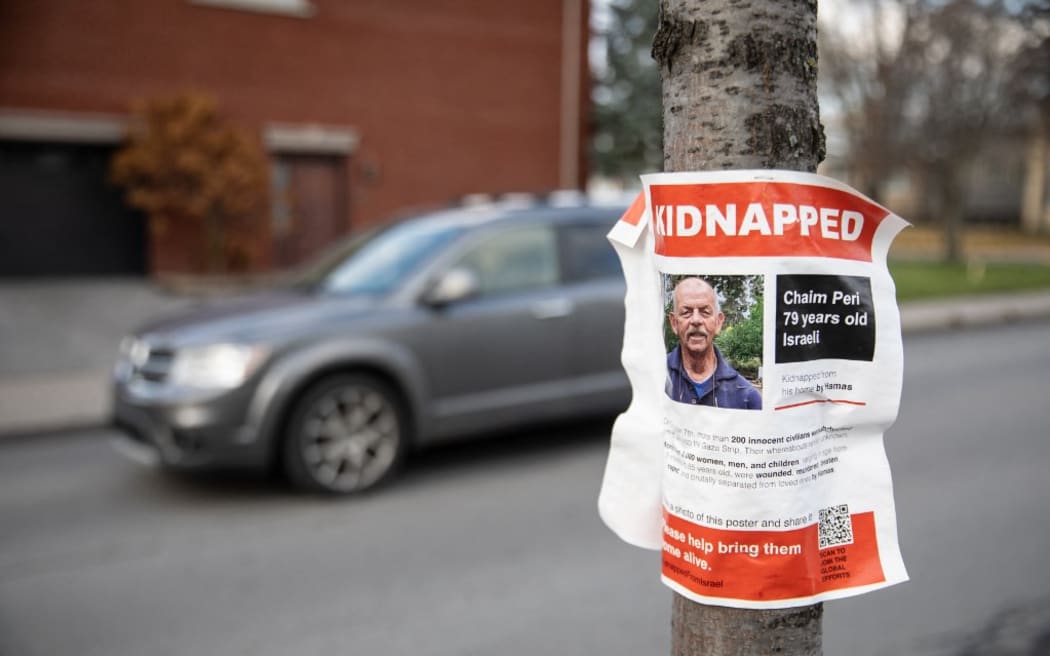 A poster showing the photo of 79 year old Israeli hostage Chaim Peri is displayed on a tree in Hampstead, Quebec, Canada, on November 14, 2023. They had feared it, but were nevertheless surprised by the scale: in the town of Hampstead, populated mainly by Canadians of the Jewish faith, the inhabitants were appalled and worried about the outbreak of anti-Semitic acts. And even more so since the upsurge in anti-Semitic acts: last week, Jewish schools in Montreal were shot at night, one twice. Two Molotov cocktails had hit a synagogue a few days earlier. "We have received requests from various organizations and residents in general to display posters of the Israeli hostages. We absolutely wanted to meet these demands," says Mayor Jeremy Levi, 39. (Photo by Alexis Aubin / AFP)
