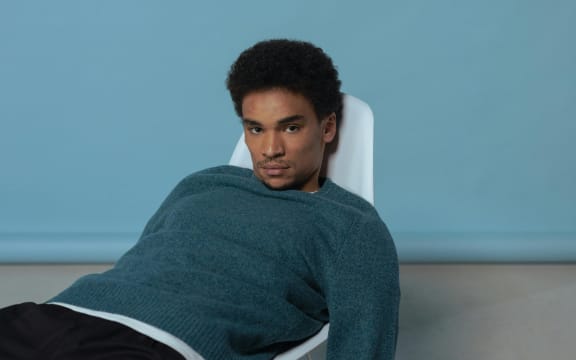 A man in a blue sweatshirt slouching on a chair