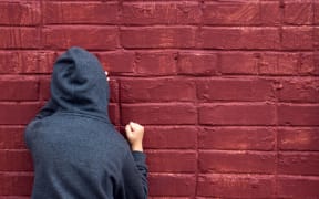 Worried depressed sad teen boy (child) crying near brick wall