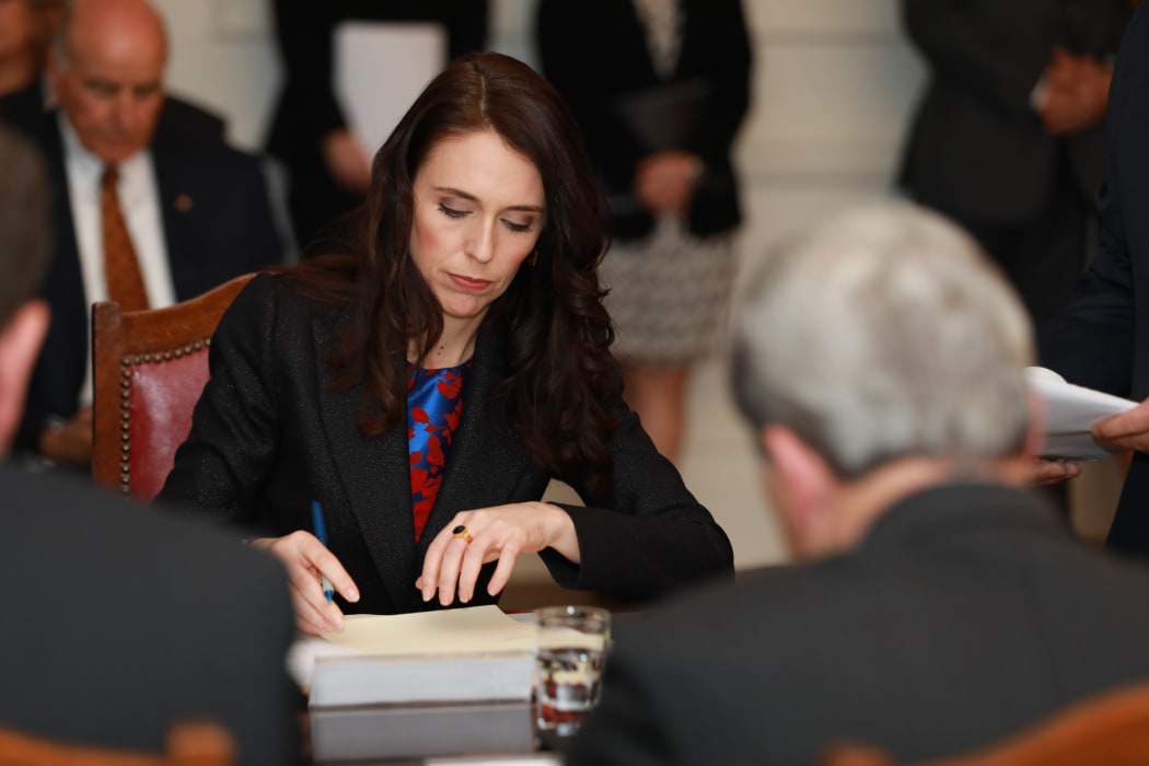 Prime Minister Jacinda Ardern signs the documentation.