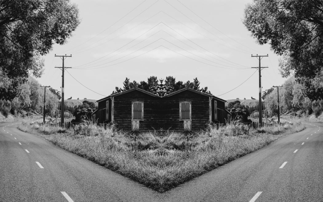 A gothic, black-and-white mirror image of a street in Whanganui featuring a ram-shackle house and powerlines.