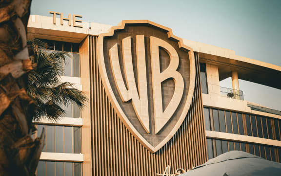 A buliding displays the Warner Bros 'WB' logo in shades of brown.