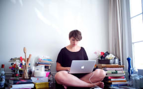 Delaney Mes sitting on the floor, working on her laptop.