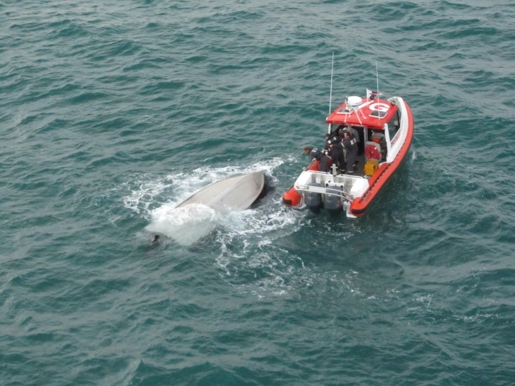 The Coastguard vessel next to the overturned boat.