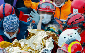 Elif Perincek, a three-year-old survivor, holding the thumb of a rescue worker as she is carried out of a collapsed building after an earthquake in Izmir on 2 November, 2020.