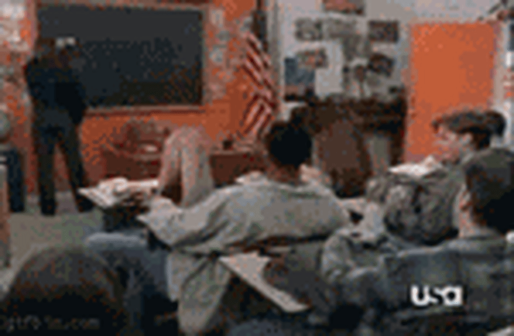 Chick Norris stands at a blackboard, catches a ball of paper, and throws it back at the student who threw it.