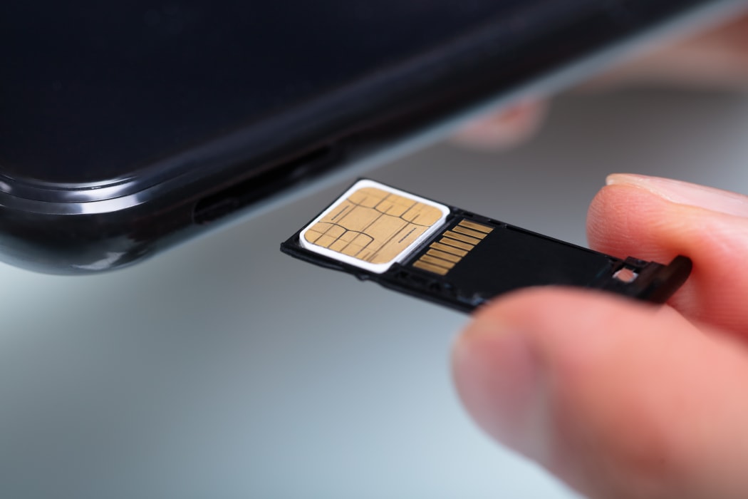 Close-up Of A Person's Hand Inserting Sim Card In Cellphone.