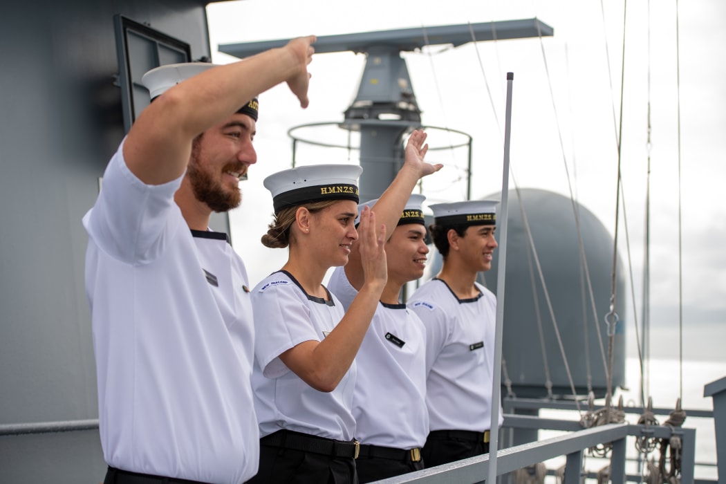 Crew onboard the HMNZS Aotearoa wave to onlookers.