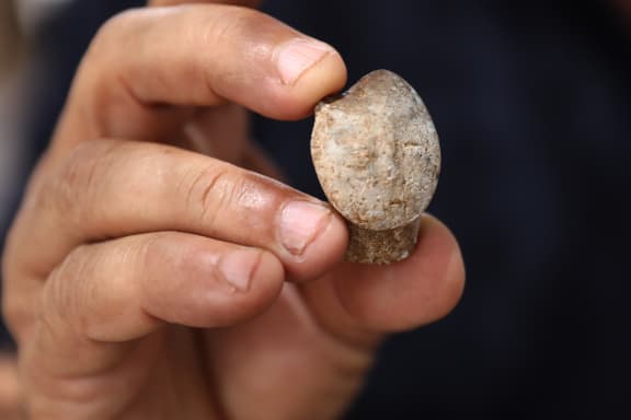Archeologist of the Israel Antiquities Authority Hamoudi Khalaily holds a 9000-year-old stone figurine depicting a human face, found at the excavation site of a settlement from the Neolithic Period (New Stone Age).