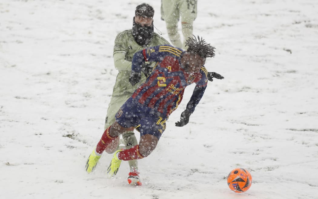 Emeka Eneli #14 of Real Salt Lake is tripped up by Eduard Atuesta #20 of the Los Angeles Football Club during the first half of their game at the America First Field.