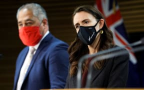Minister Peeni Henare speaks to media while Prime Minister Jacinda Ardern looks on during a press conference at Parliament on September 02, 2021