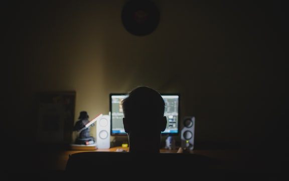 Male in front of a computer screen in the dark.