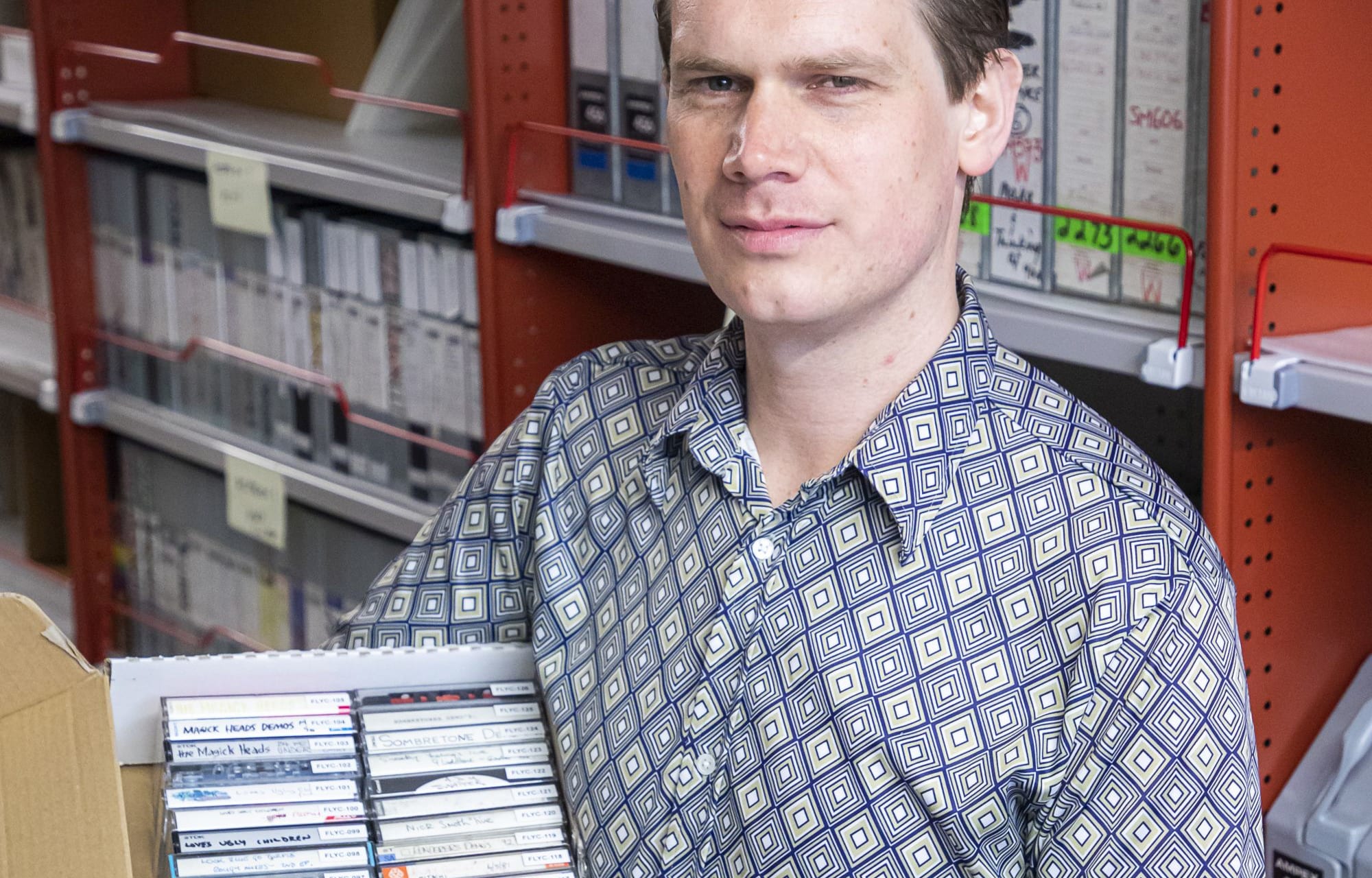 William Daymond, Librarian pictured with Flying Nun collection at The Alexander Turnbull Library.