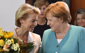 German Defence Minister Ursula von der Leyen talks to German Chancellor Angela Merkel after receiving flowers as she leaves the weekly cabinet meeting on 17 July, 2019 in Berlin.