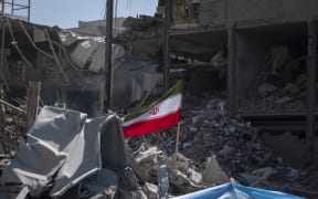 A national flag on the ruins of a police station that is struck on Monday during US-Israeli attacks in Tehran, Iran, on 3 March, 2026.