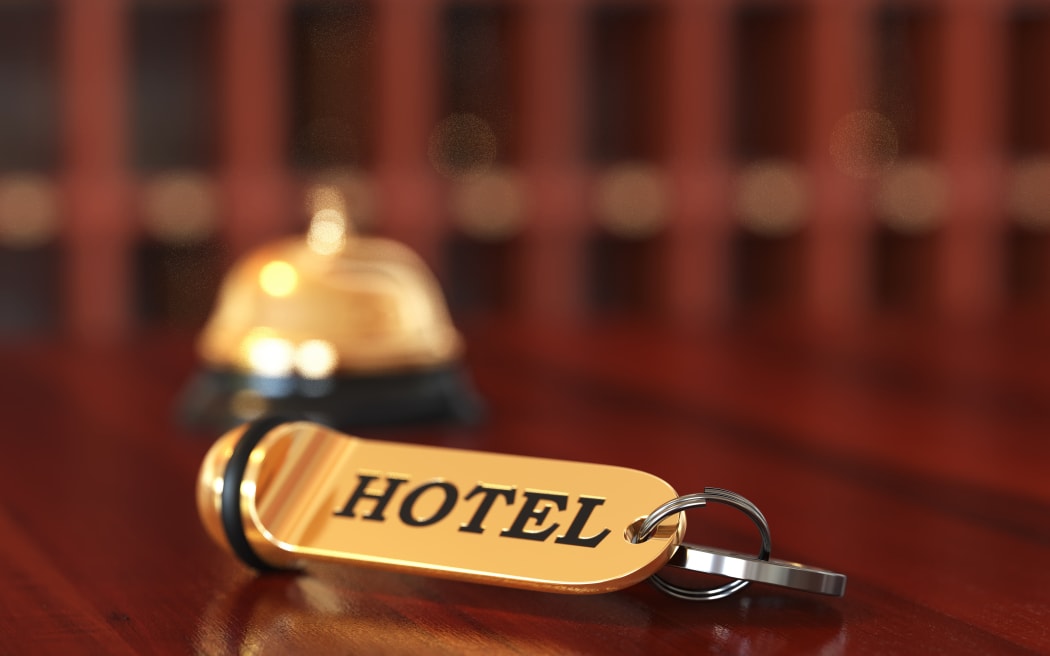 Close up of room access key and bell on wooden reception desk. Soft focus illustration