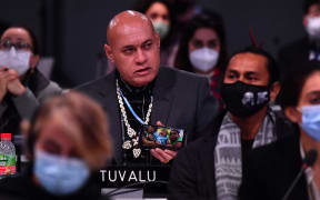 Tuvalu's Finance Minister Seve Paeniu shows a photo of his grandchildren as he speaks during an intervention at an informal plenary during the COP26 UN Climate Change Conference in Glasgow on November 13, 2021.