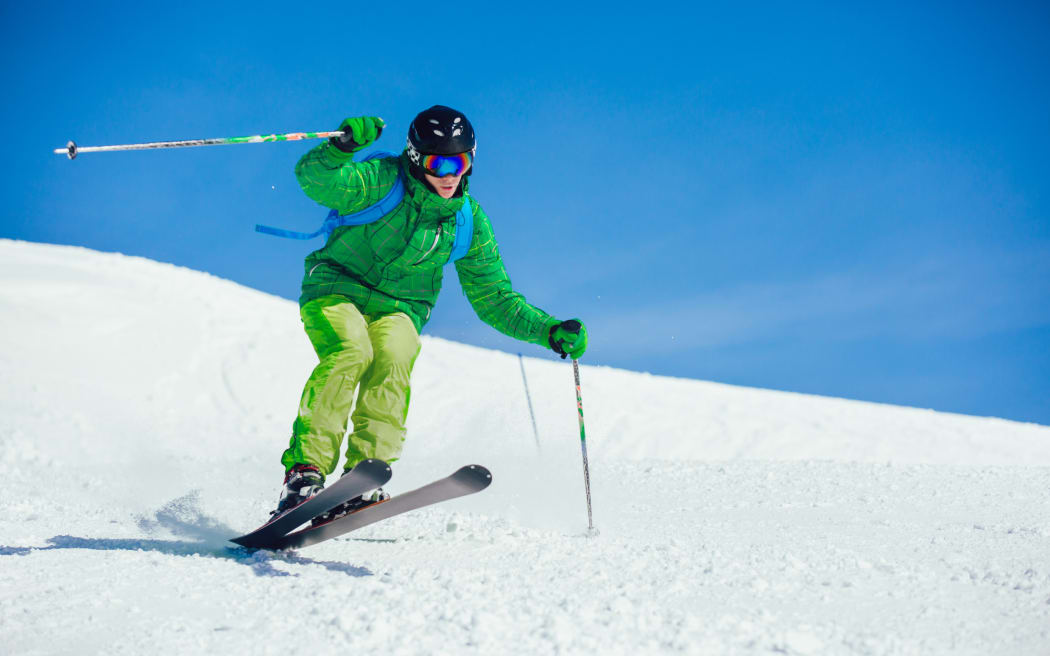 Young athlete freestyle Skier having fun while running downhill in beautiful landscape on sunny day during winter season