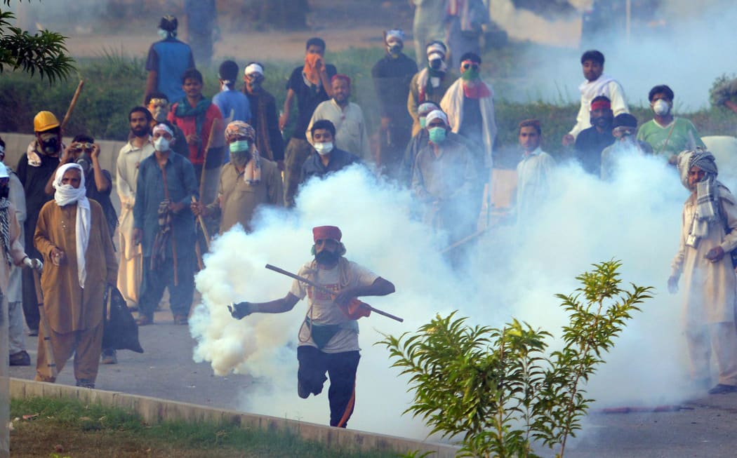 A Pakistani supporter of the Canadian cleric Tahir ul Qadri returns a tear gas shell towards police during clashes with security forces.